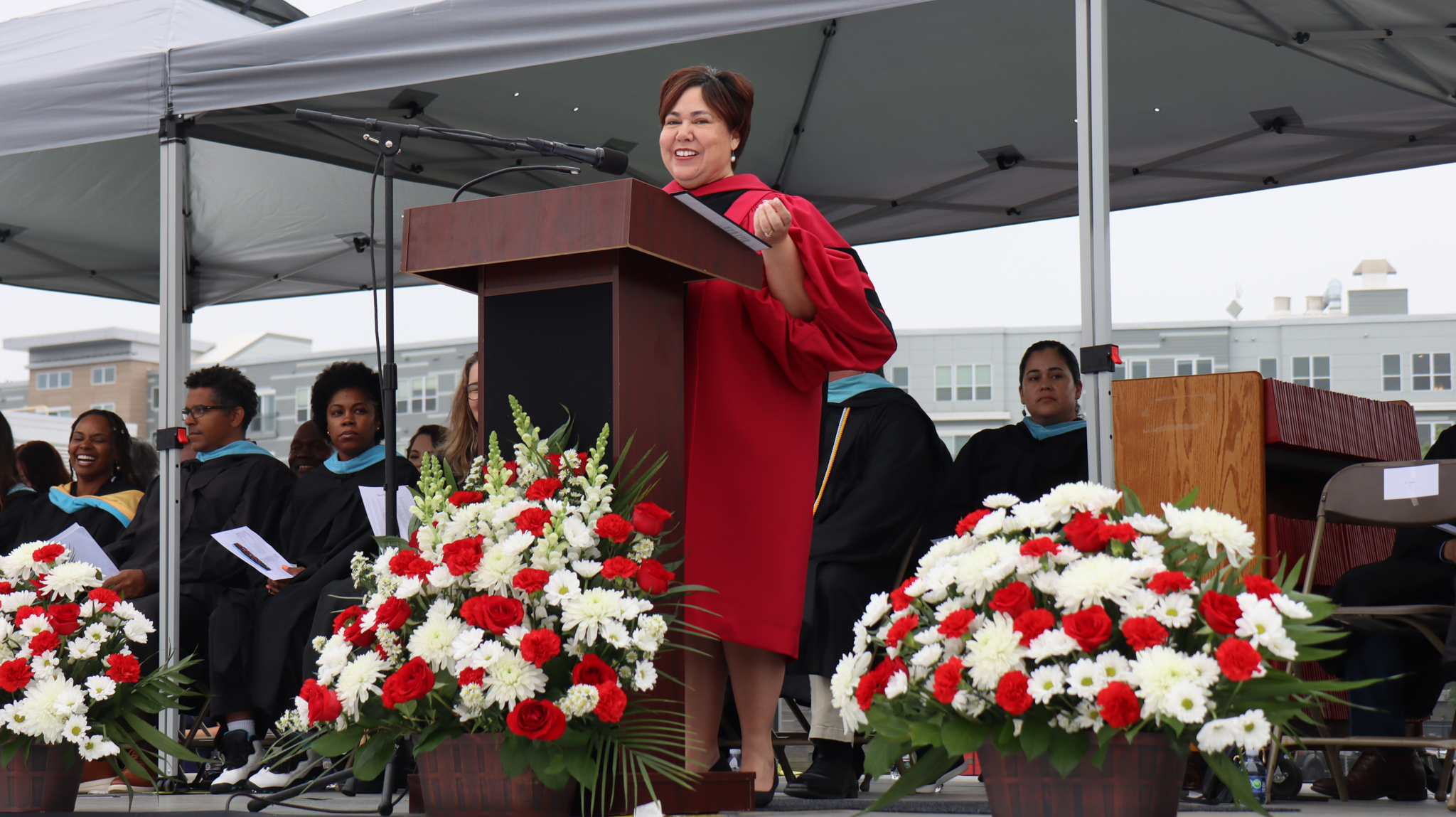 CPS Superintendent Dr. Almi G. Abeyta smiling in front of a podium as she speaks at Graduation